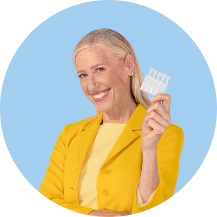 A woman smiling holding 5 vials of Xiidra eye drops