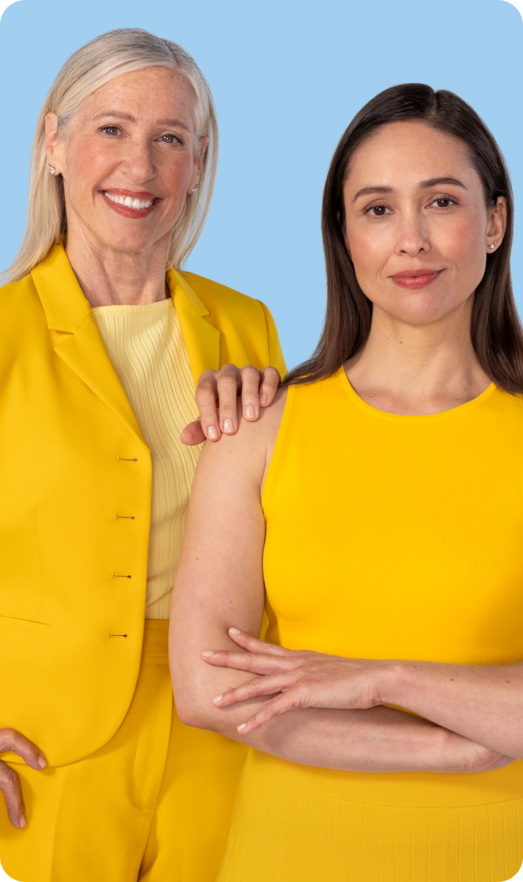 Two women one older one younger standing side by side, one has their hand on the others shoulder