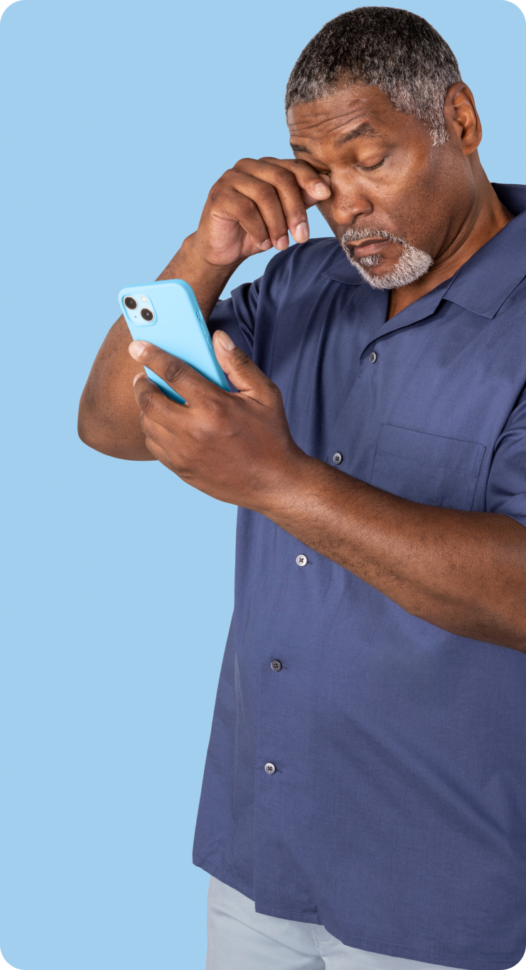 Man with itchy eyes rubs his eye while holding his phone